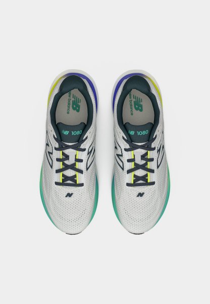 Par de zapatillas de running New Balance 1080 blancas con cordones negros y detalles en verde, azul y amarillo, vistas desde arriba sobre un fondo blanco.