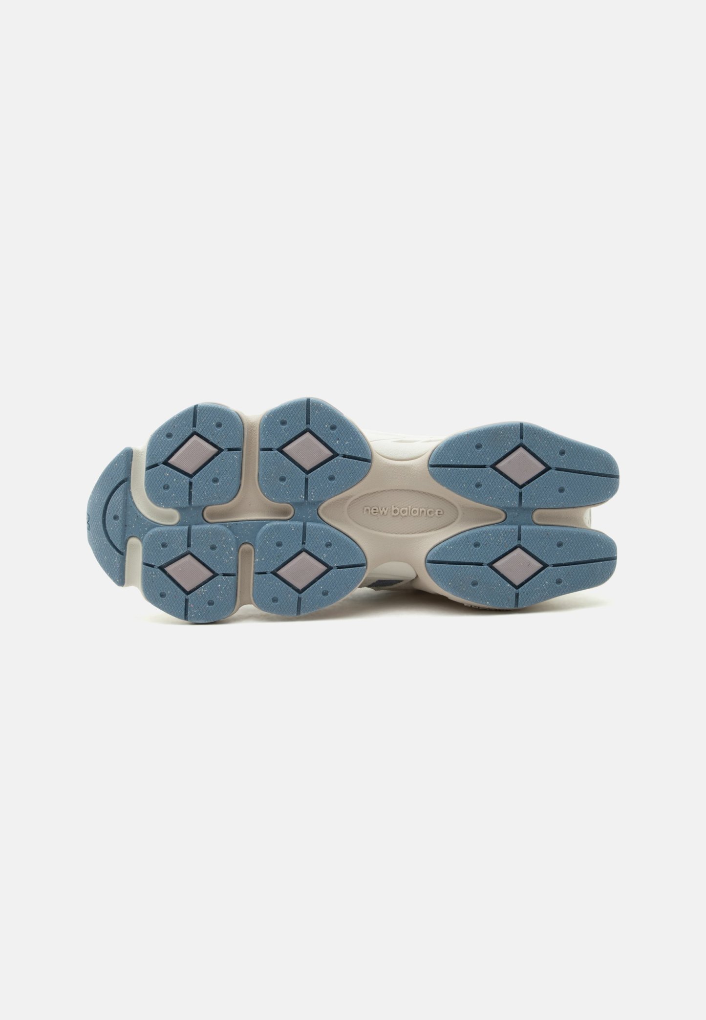 Suela de zapatilla beige New Balance con secciones de agarre de goma azul con formas de diamante y patrón de banda de rodadura texturizado.