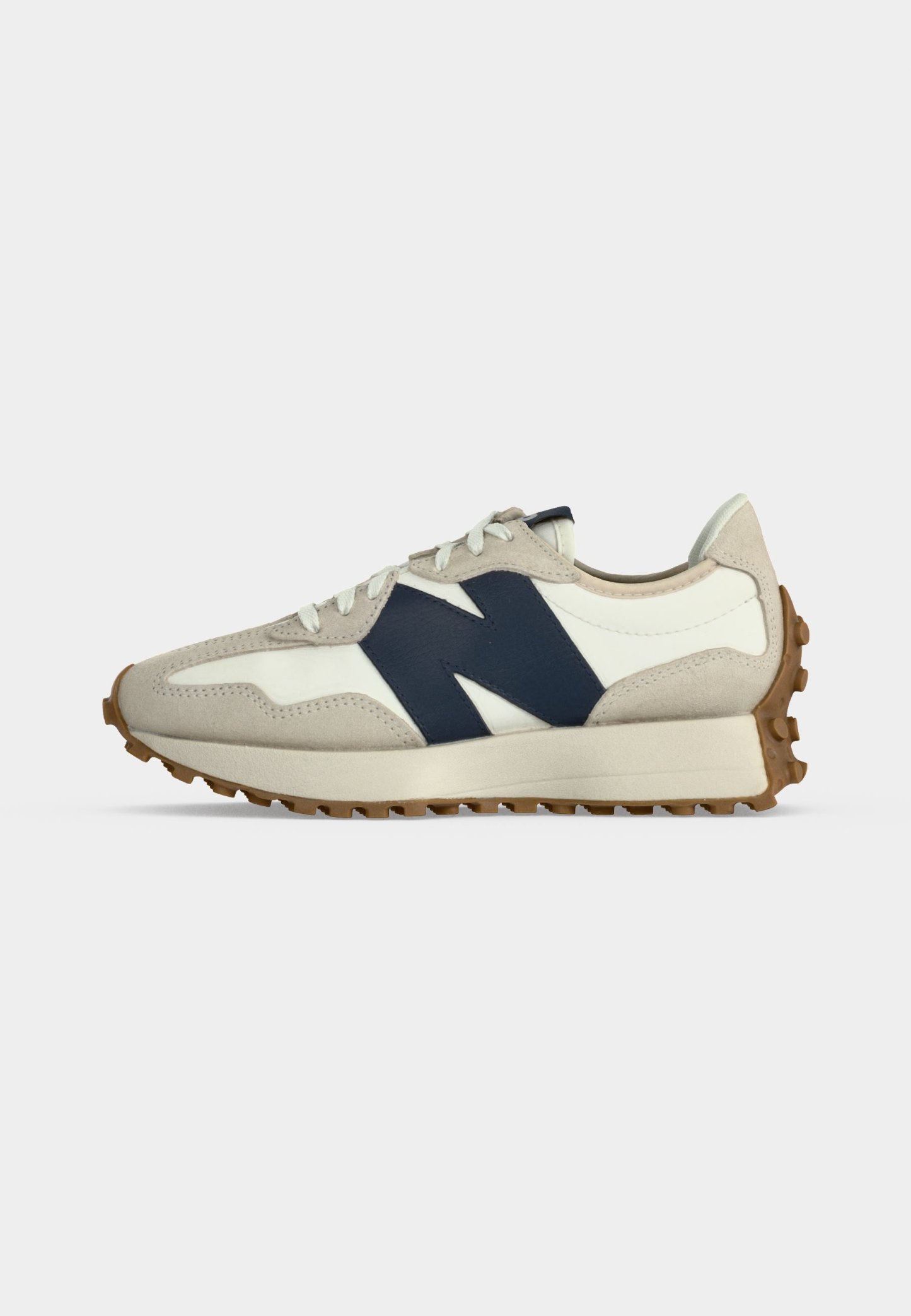 Zapatilla beige y blanca con logo lateral "N" en azul marino, cordones blancos y suela de goma marrón texturizada, mostrada de perfil sobre fondo claro.