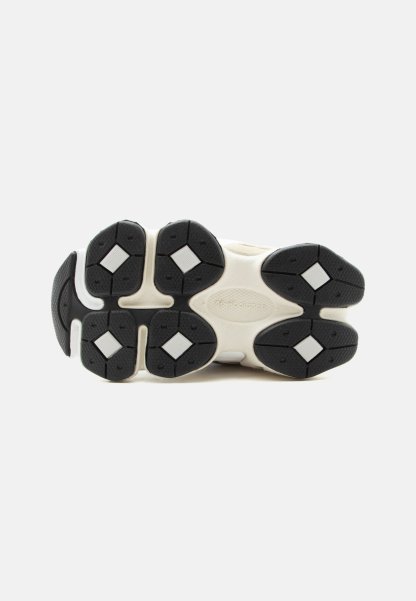 Suela de zapatilla blanca con almohadillas de tracción de goma negra que presentan inserciones blancas en forma de diamante sobre un fondo liso.