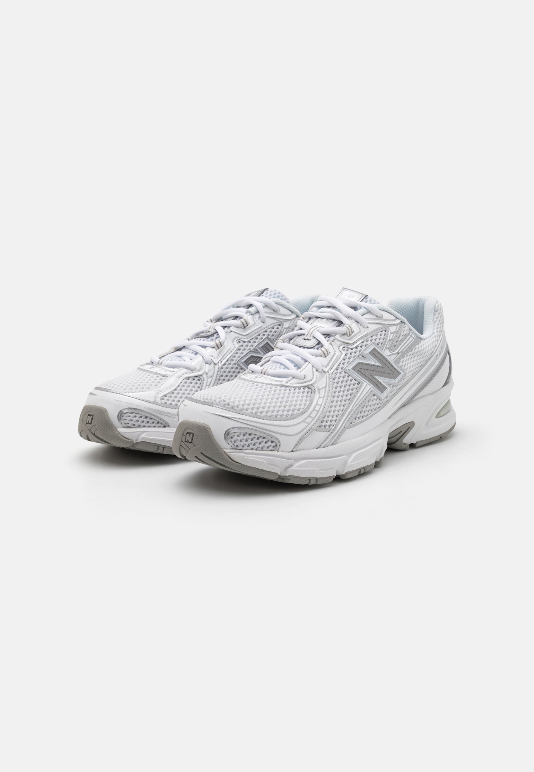 Zapatillas deportivas blancas con parte superior de malla, acentos grises, sistema de cordones y suelas acolchadas diseñadas para la comodidad y el soporte.