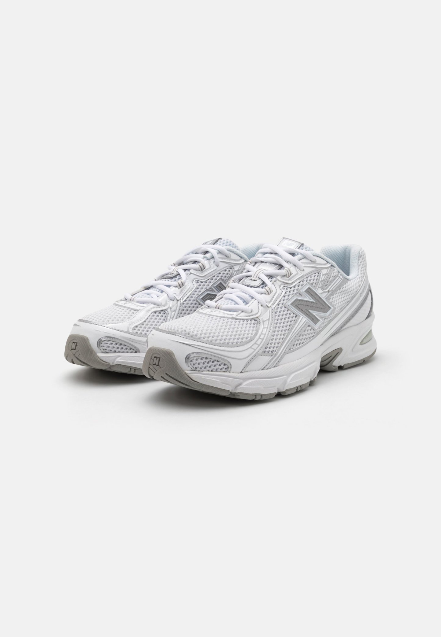 Zapatillas deportivas blancas con parte superior de malla, acentos grises, sistema de cordones y suelas acolchadas diseñadas para la comodidad y el soporte.