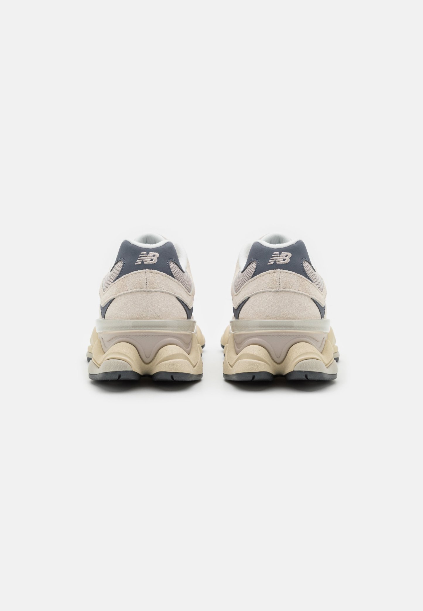 Zapatillas de deporte color beige claro con parte superior de ante y malla, con un acento en gris oscuro, suela acolchada y diseño de tacón elevado.