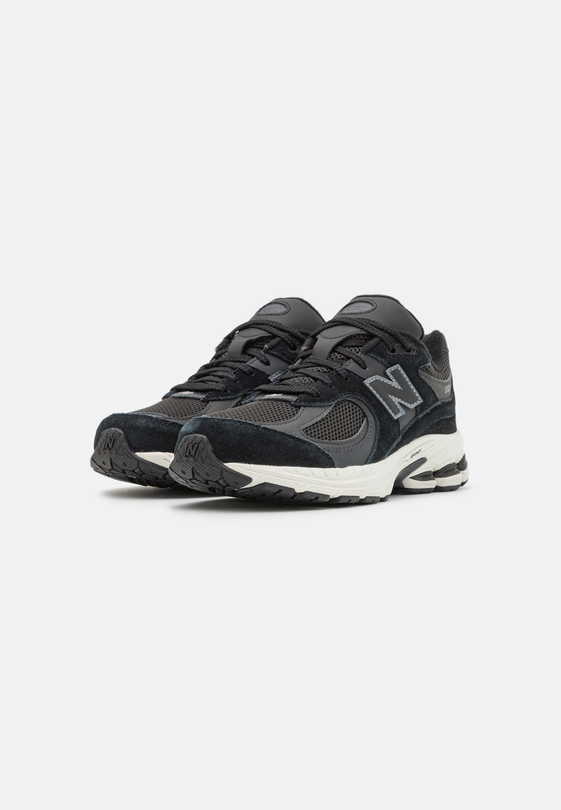 Zapatillas deportivas negras con una mezcla de materiales de malla y ante, que cuentan con un destacado logo 'N', lengüeta acolchada y suelas texturizadas.