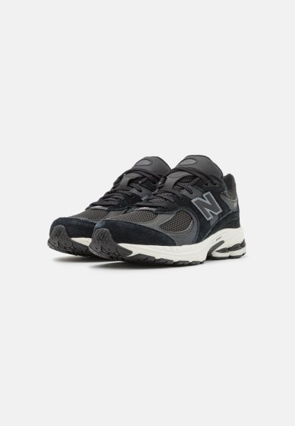 Zapatillas deportivas negras con una mezcla de materiales de malla y ante, que cuentan con un destacado logo 'N', lengüeta acolchada y suelas texturizadas.