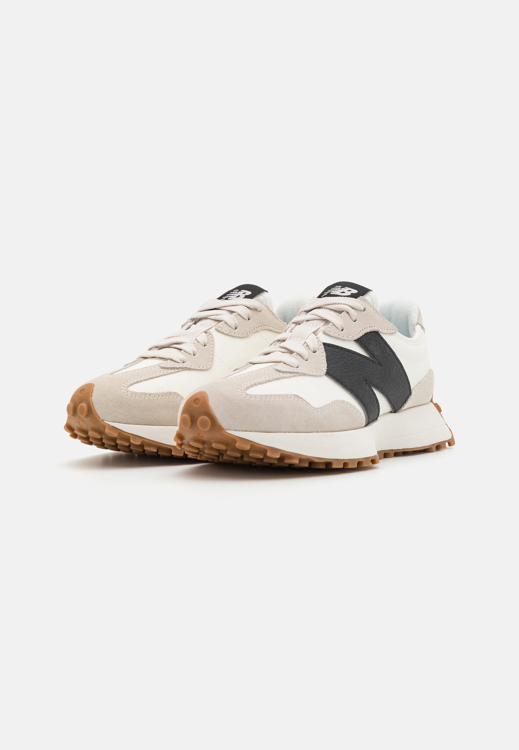 Par de zapatillas New Balance blancas y beige con logo negro y suela de goma texturizada, mostradas en un ligero ángulo sobre fondo blanco.
