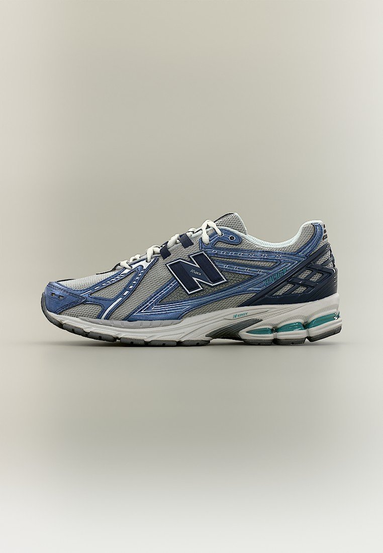Zapatilla de running con diseño en azul, gris y blanco, parte superior de tela de malla, suela acolchada y logo de New Balance en el lateral.