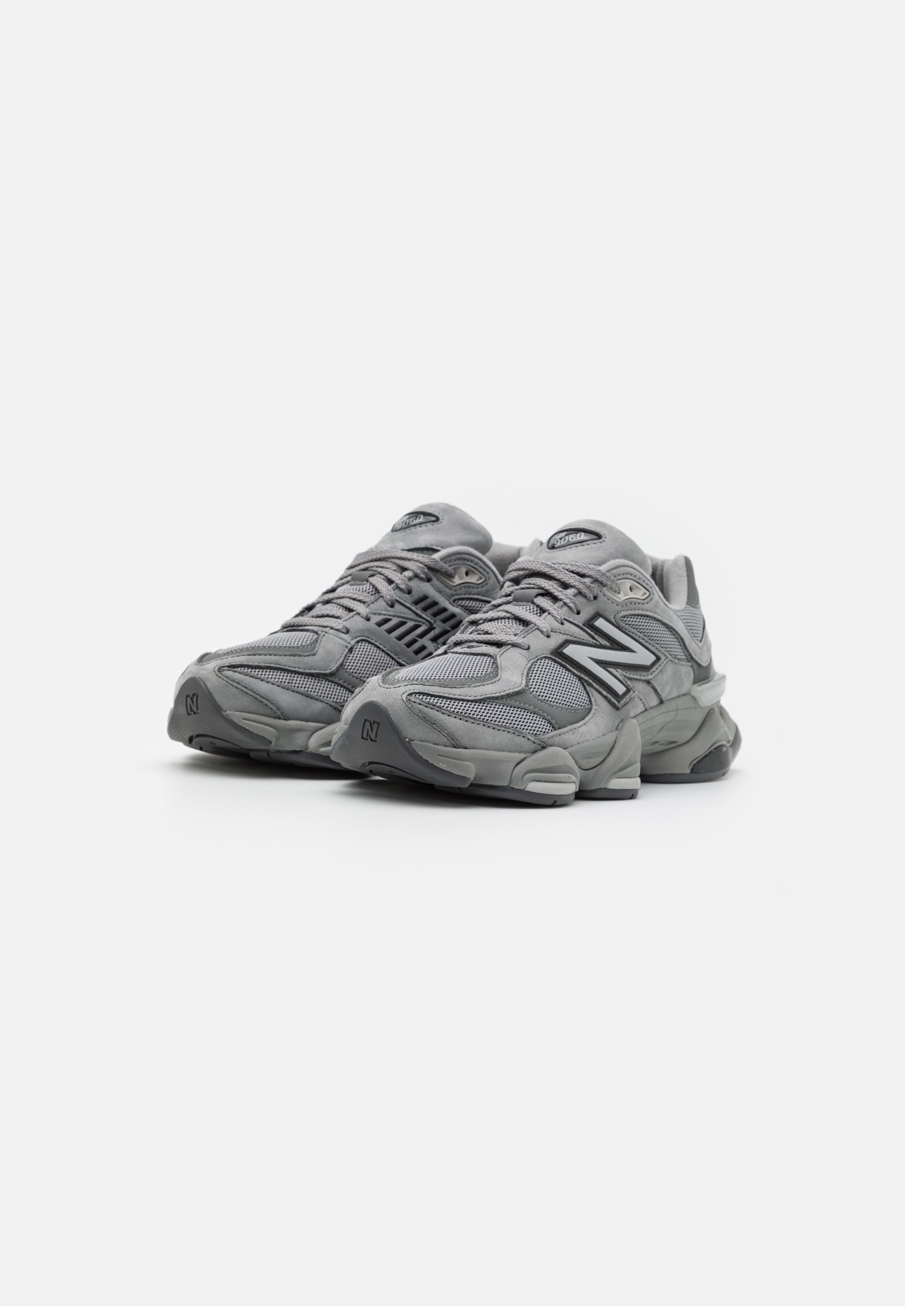 Par de zapatillas de running New Balance grises con detalles de malla y ante, suelas gruesas y cierre de cordones sobre un fondo blanco liso.