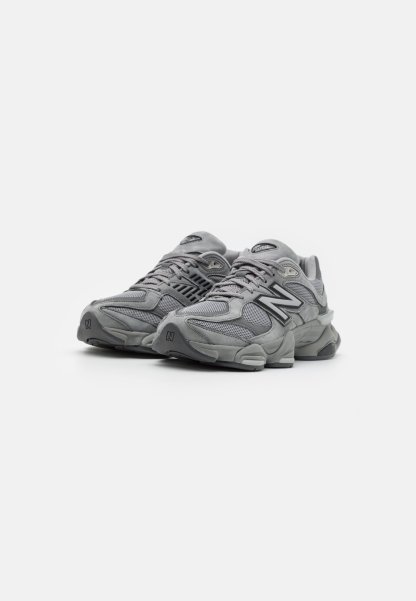 Par de zapatillas de running New Balance grises con detalles de malla y ante, suelas gruesas y cierre de cordones sobre un fondo blanco liso.