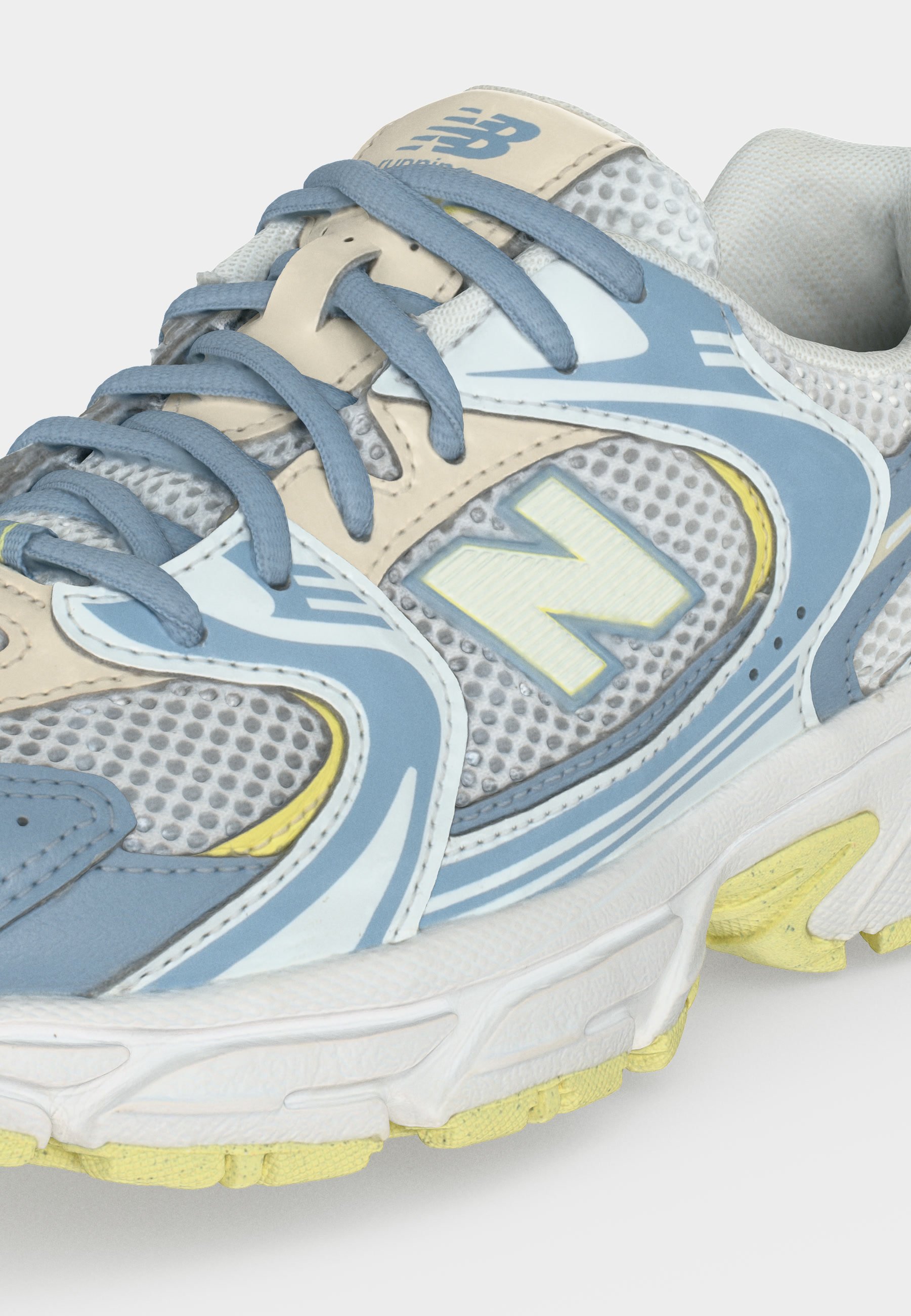 Primer plano de una zapatilla de running New Balance gris, azul y amarilla con malla y superposiciones sintéticas y logo visible en el lateral y la lengüeta.