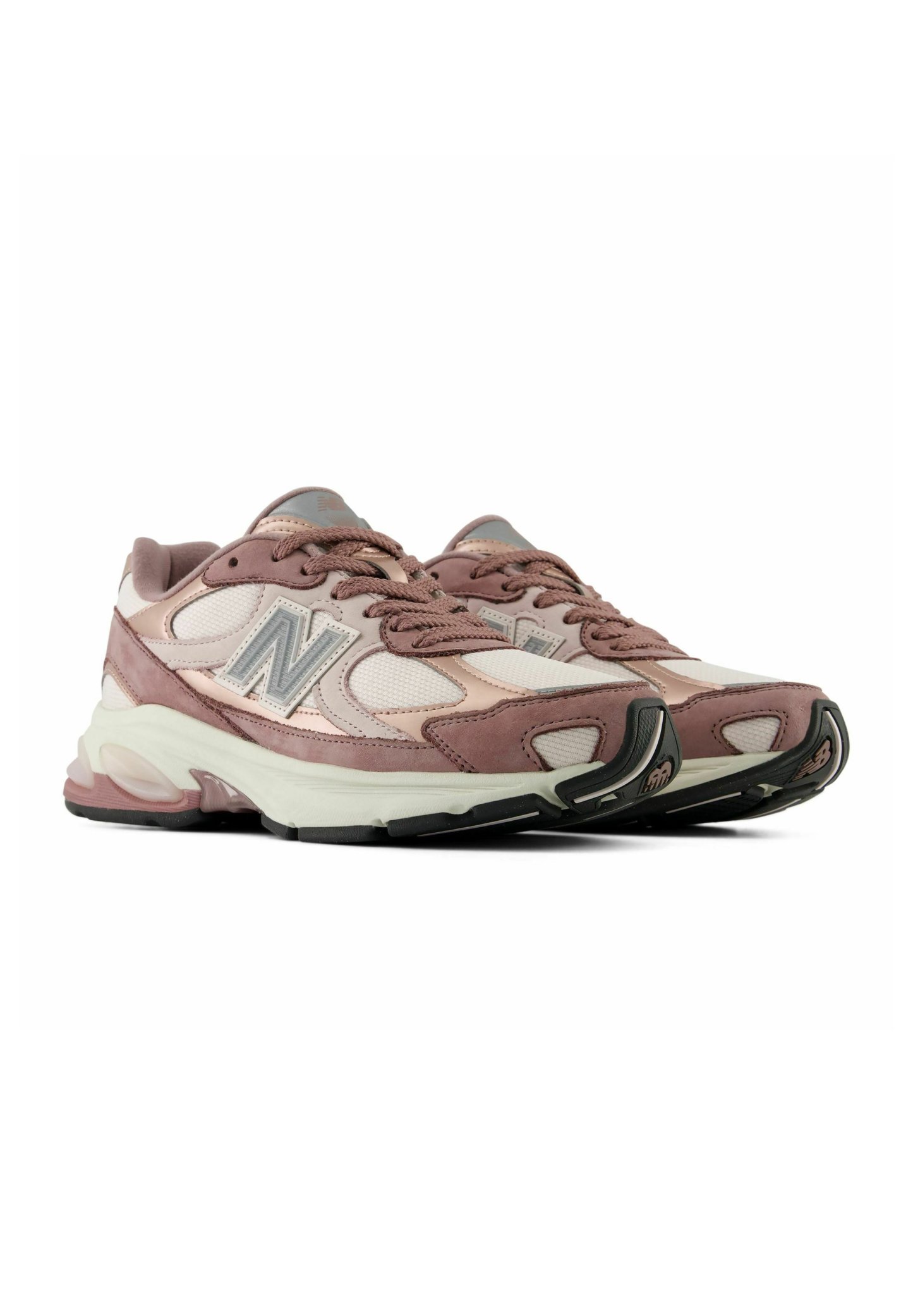 Par de zapatillas deportivas New Balance rosa y blancas con parte superior de malla y ante y suelas blancas gruesas, vistas desde un ángulo frontal lateral.