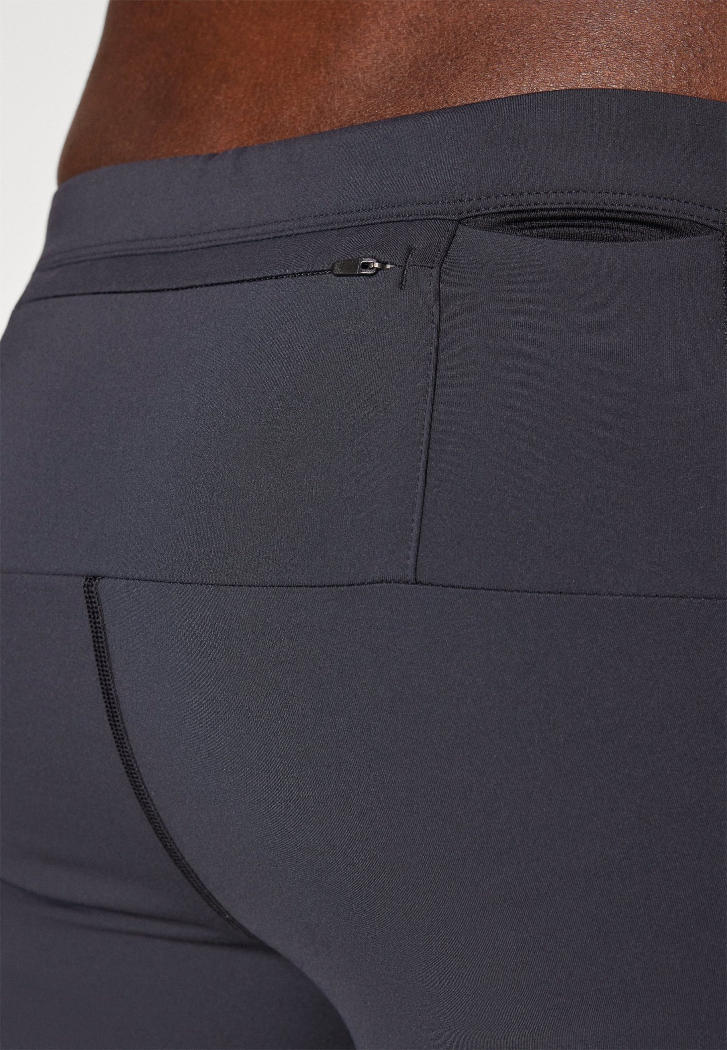 Pantalones cortos deportivos negros fabricados con tejido elástico, presentan un diseño sin costuras, un bolsillo trasero con cremallera y un detalle de costura en contraste.