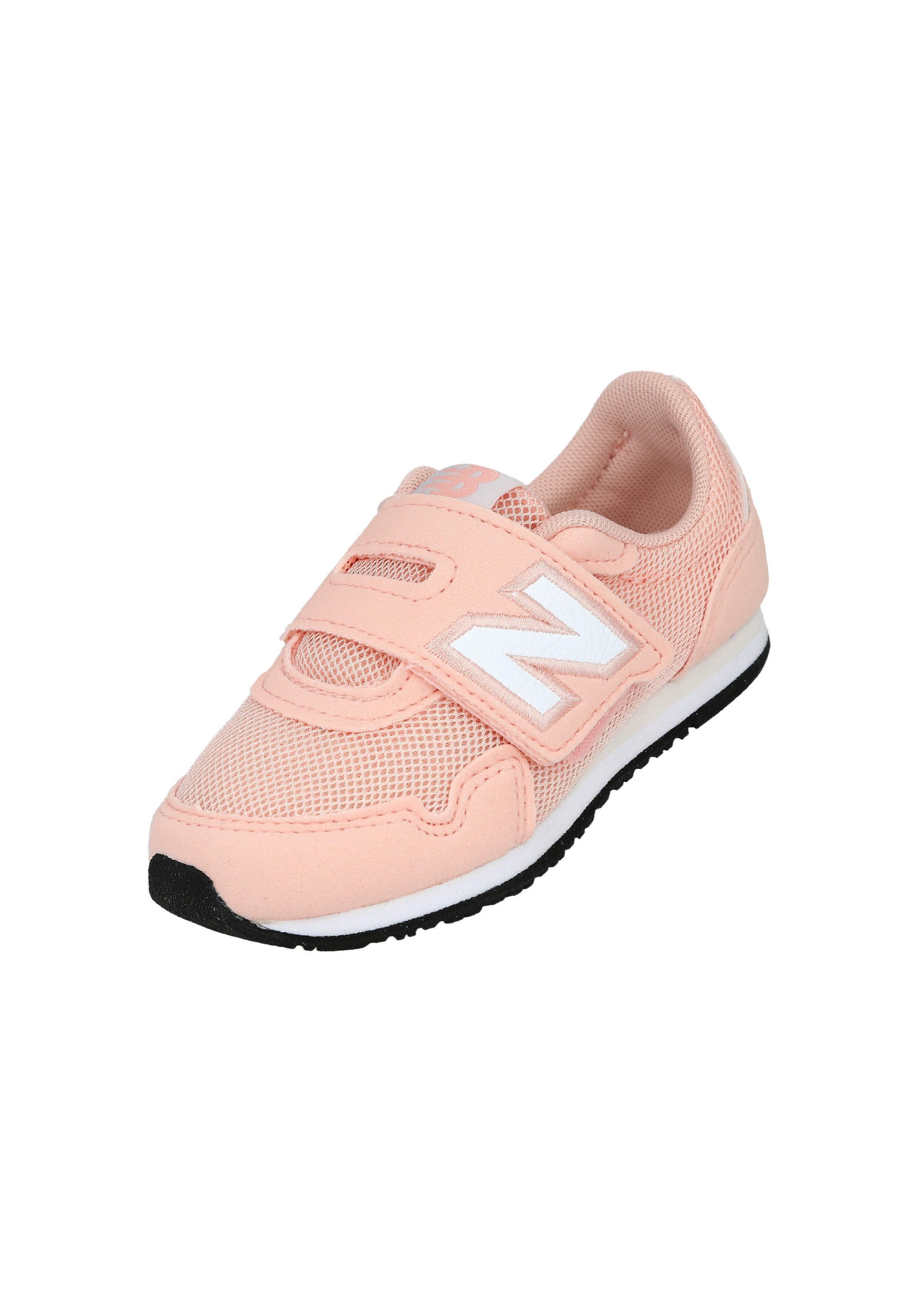 Zapatilla deportiva para niño de color rosa claro con parte superior de malla, suela blanca, dibujo de la suela negra y logo blanco "N" en una correa de velcro.