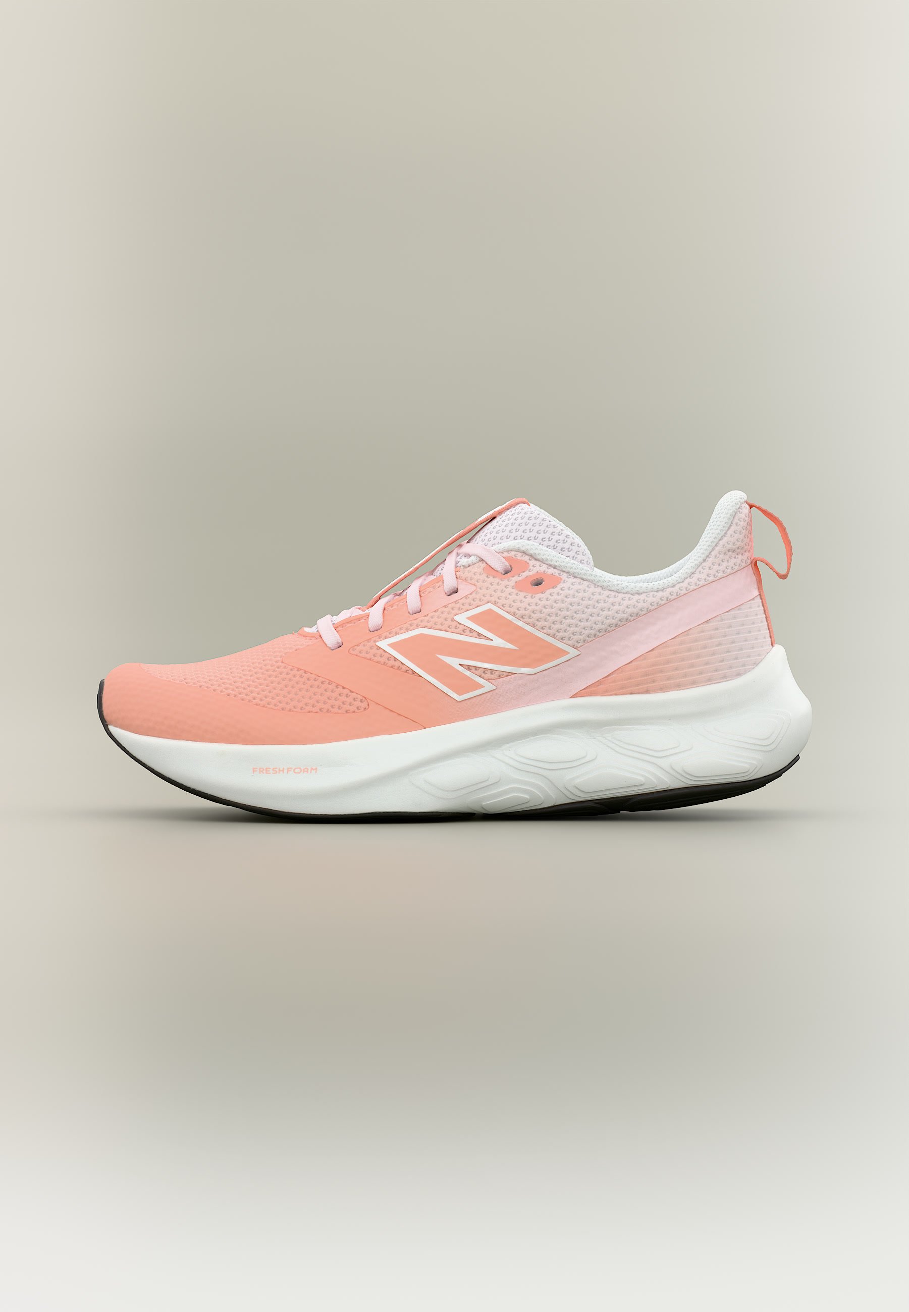 Zapatilla deportiva rosa claro y blanca con suela blanca, parte superior de malla, logo lateral y cordones sobre un fondo neutro.