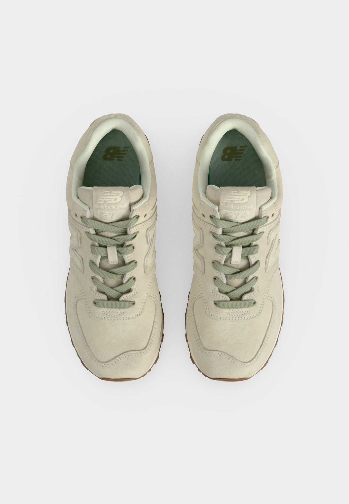 Par de zapatillas New Balance beige con cordones verdes y forro interior, mostradas desde arriba sobre un fondo blanco.