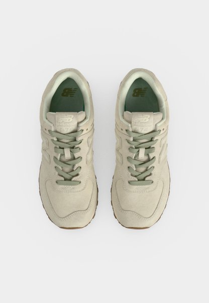 Par de zapatillas New Balance beige con cordones verdes y forro interior, mostradas desde arriba sobre un fondo blanco.