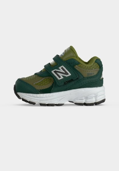 Zapatilla para niño en verde y verde oscuro con suela blanca y dos tiras de velcro, con un gran logo blanco "N" en el lateral.