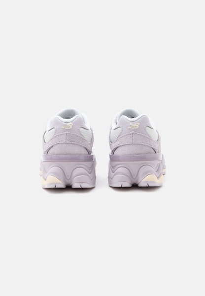 Par de zapatillas New Balance de color lila claro vistas desde atrás con suelas gruesas y onduladas sobre un fondo blanco.