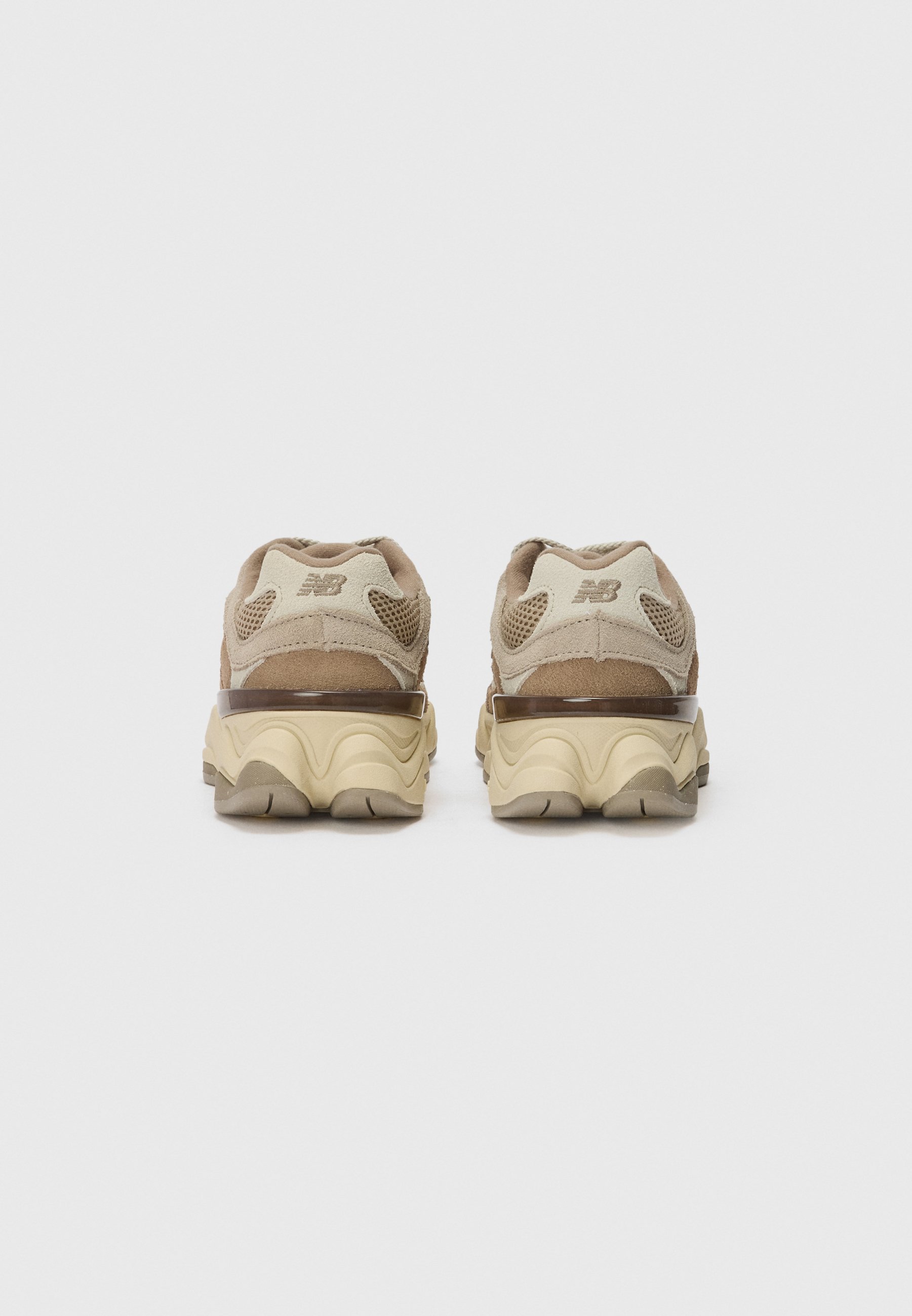 Zapatillas marrones y beige con un upper de ante texturizado, paneles de malla y una suela con patrón de olas. Presentan un logo reflectante en el talón.