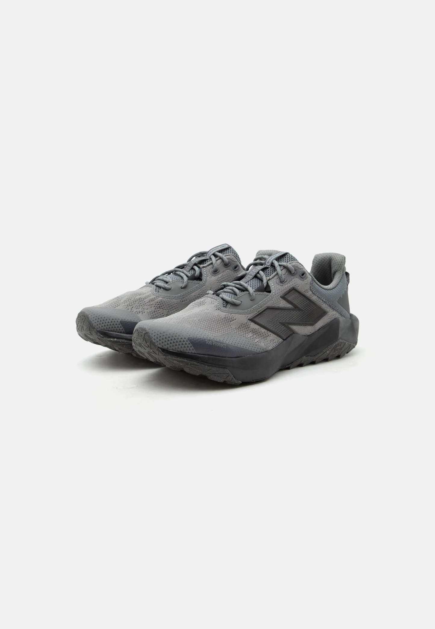 Par de zapatillas deportivas grises con parte superior de malla, suelas negras y grandes logotipos "N" en los laterales, colocadas sobre fondo blanco.