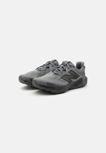Par de zapatillas deportivas grises con parte superior de malla, suelas negras y grandes logotipos "N" en los laterales, colocadas sobre fondo blanco.