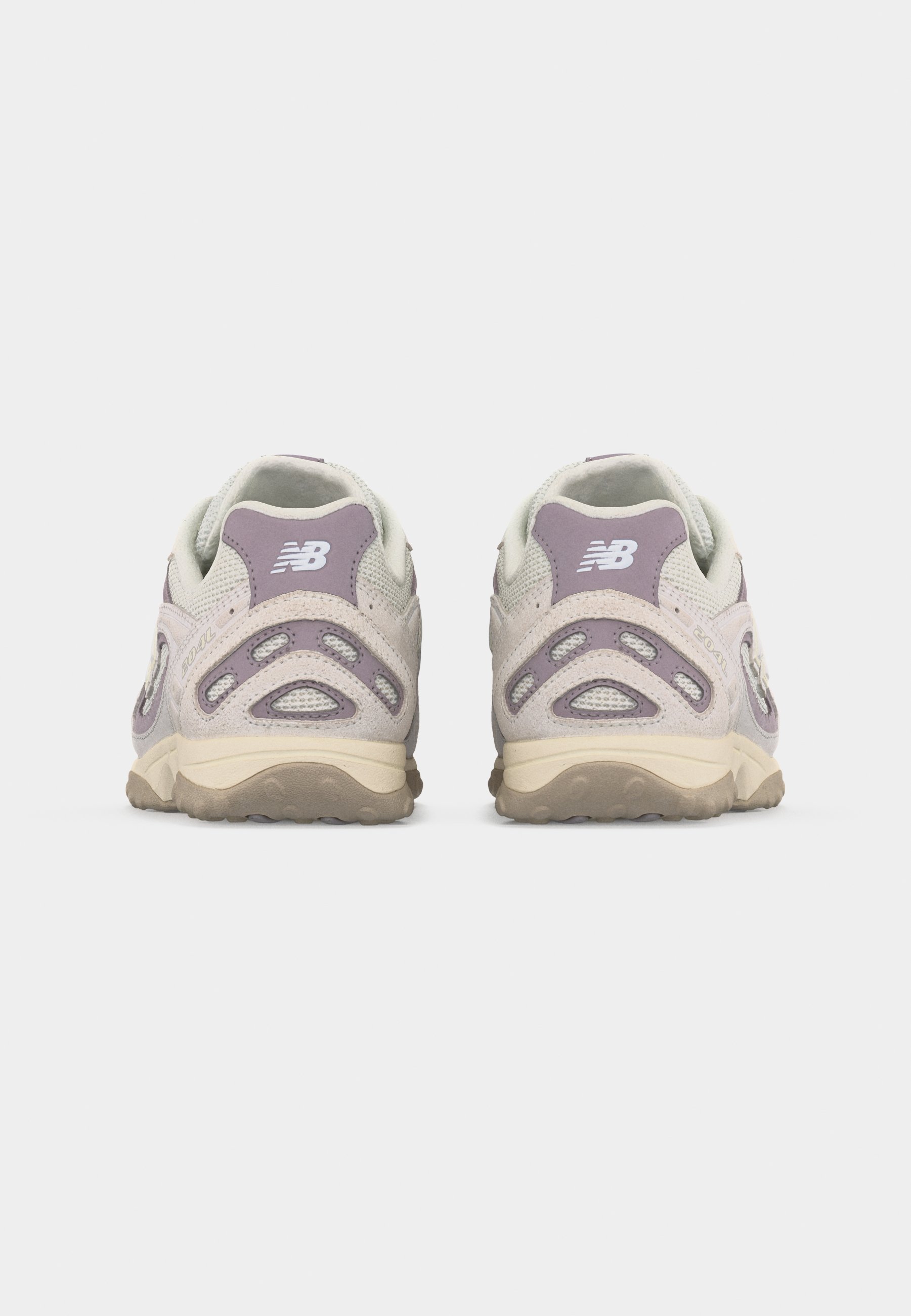 Par de zapatillas New Balance beige y moradas mostradas desde atrás sobre un fondo gris liso.