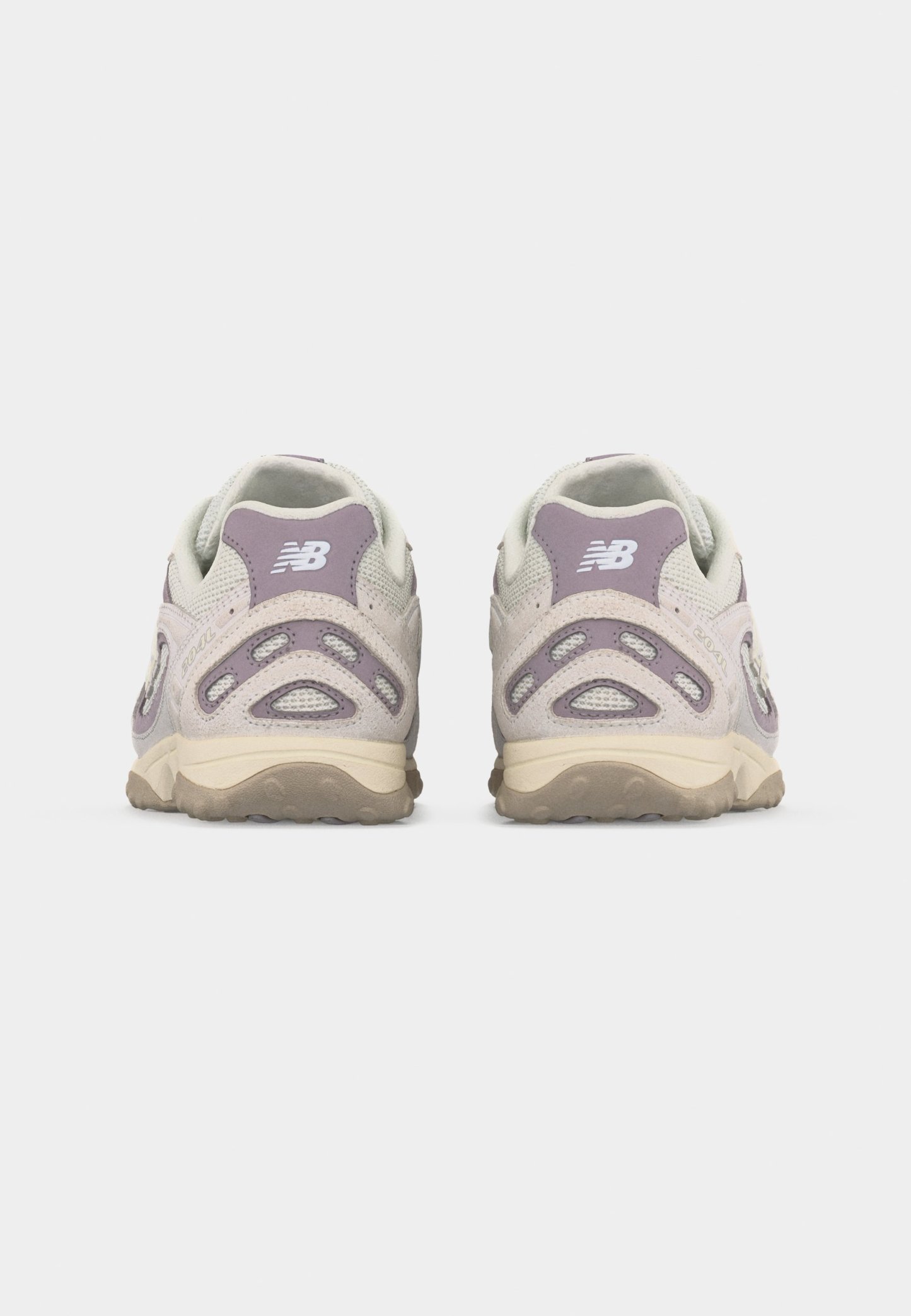 Par de zapatillas New Balance beige y moradas mostradas desde atrás sobre un fondo gris liso.