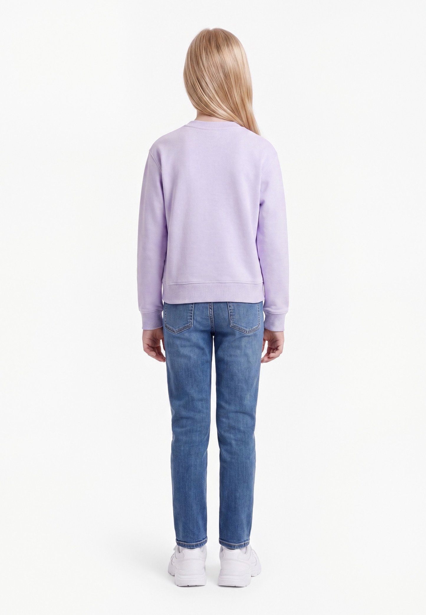 Niño con cabello largo y rubio que lleva una sudadera lila clara, vaqueros azules y zapatillas blancas, de pie de espaldas sobre un fondo blanco.