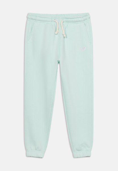 Pantalones deportivos azul claro con cintura elástica, cordón blanco, bolsillos laterales, puños elásticos y pequeño logo blanco de New Balance en el muslo izquierdo.