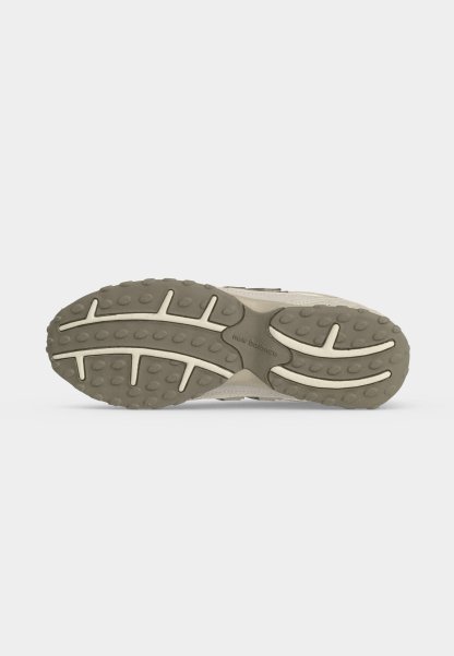 Suela de zapatilla New Balance beige con banda de rodadura texturizada y patrones de agarre, incluyendo tacos circulares y ranuras curvas para tracción.