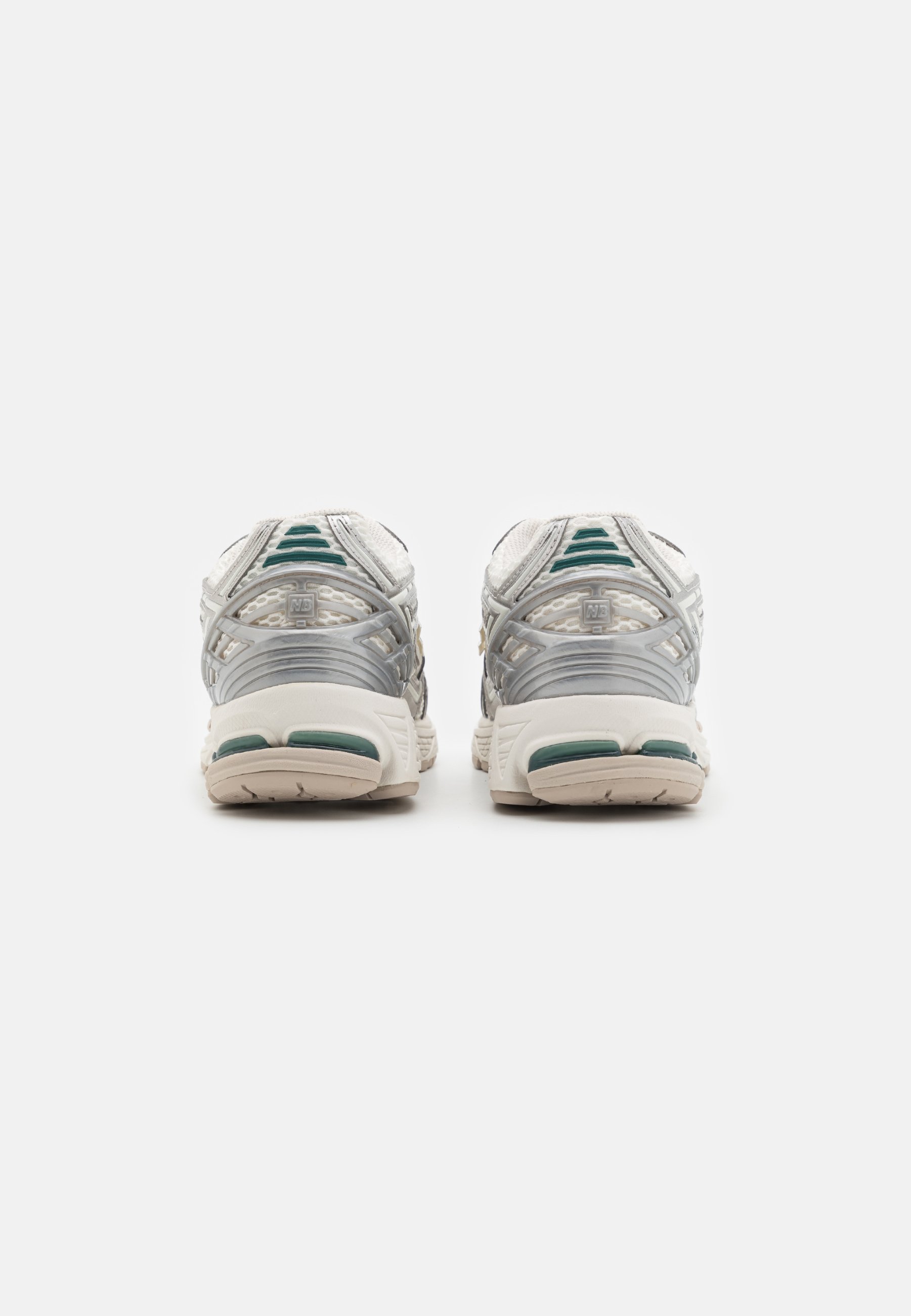 Zapatos deportivos blancos con acentos plateados, parte superior de malla texturizada, diseño de talón distintivo y detalles verdes en la suela.