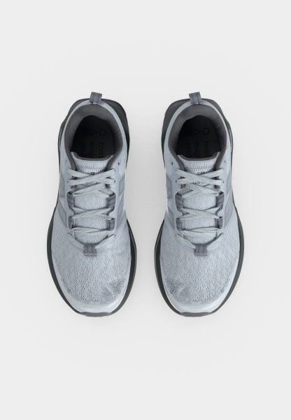 Par de zapatillas de correr grises con cordones, parte superior de malla y suelas acolchadas negras, visto desde arriba sobre un fondo blanco.