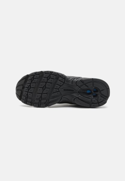Suela de zapato atlético negro con una banda de rodadura de goma estampada, que presenta ranuras y elementos de tracción, diseñada para agarre y durabilidad.
