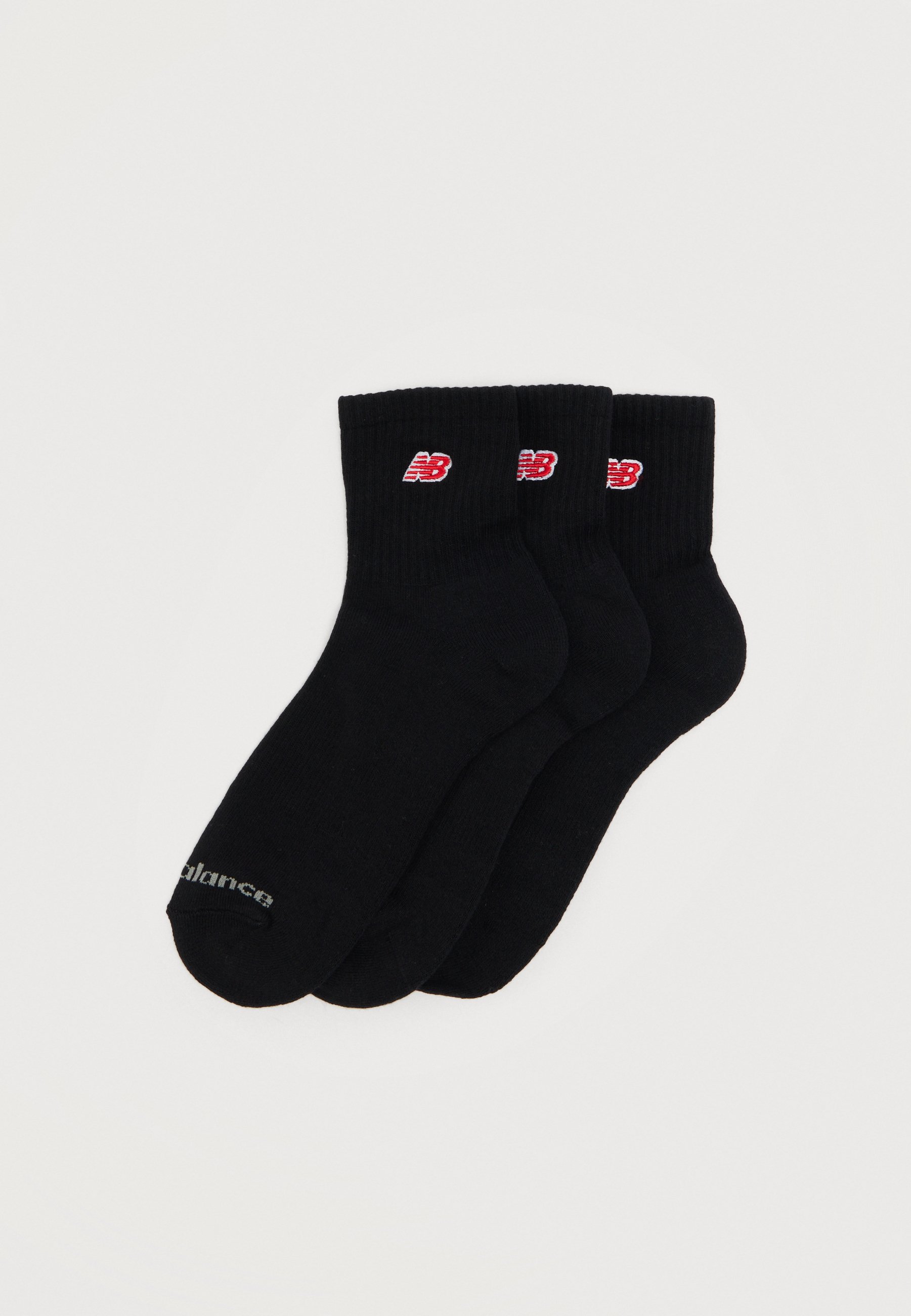 Tres pares de calcetines negros hasta el tobillo con logotipos de New Balance en rojo y blanco en los puños y una marca sutil en las puntas.