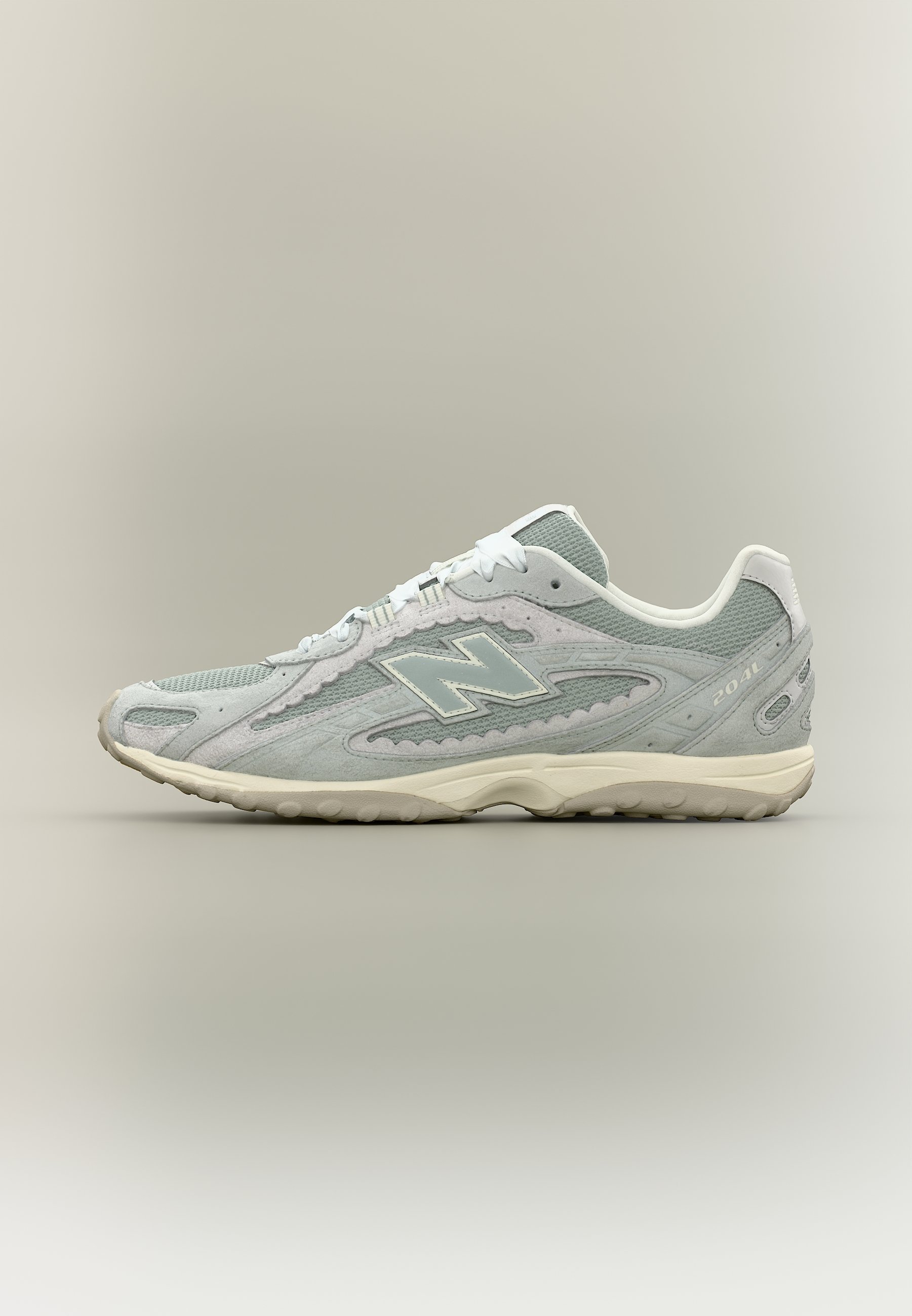 Zapatilla deportiva New Balance en gris claro y blanco, con materiales de malla y ante, diseño con cordones y suela de caucho texturizada.