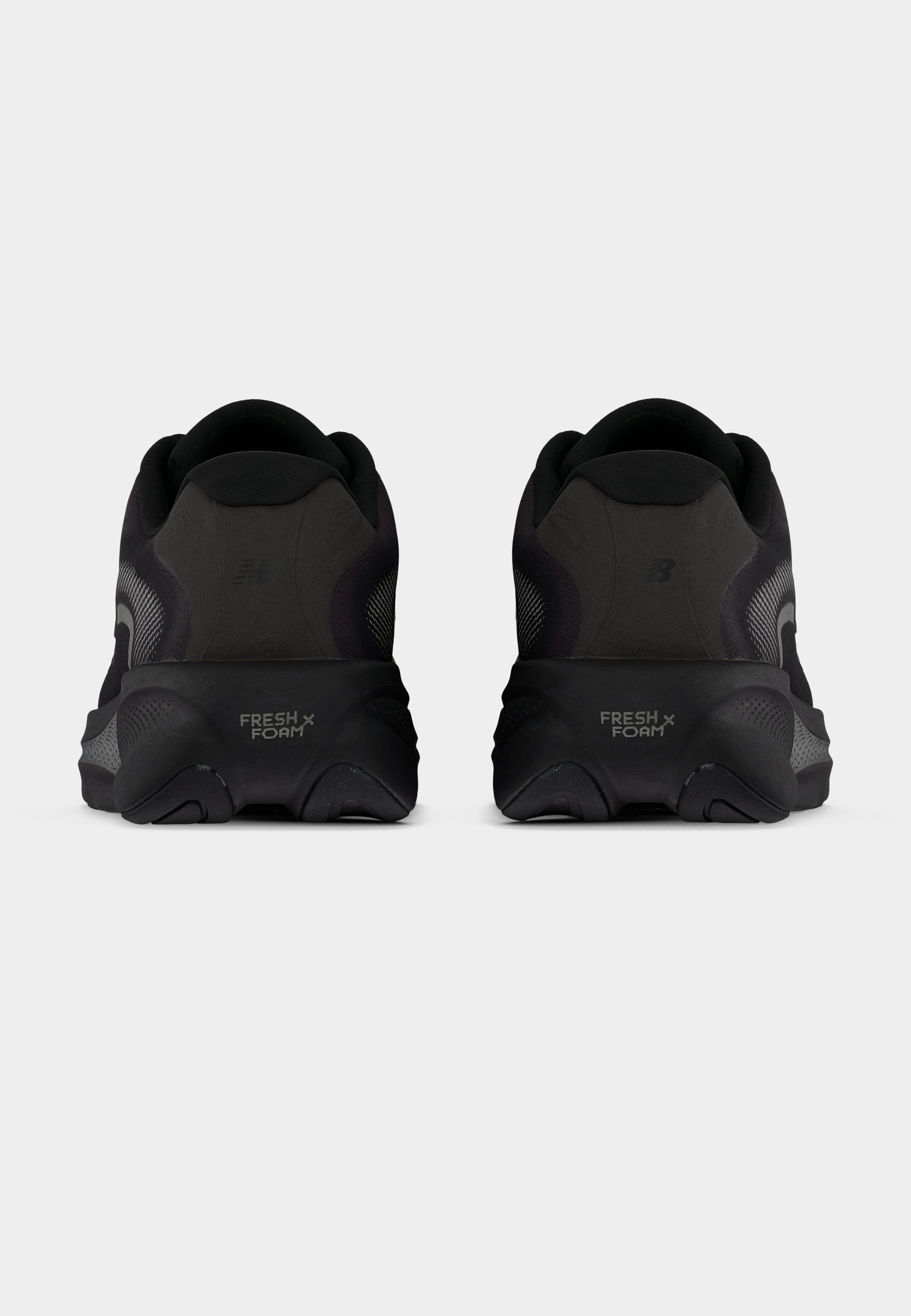 Zapatillas de running negras con parte superior de malla texturizada, suela acolchada y la marca "FRESH FOAM" en el talón. Diseño redondeado y estilo minimalista.