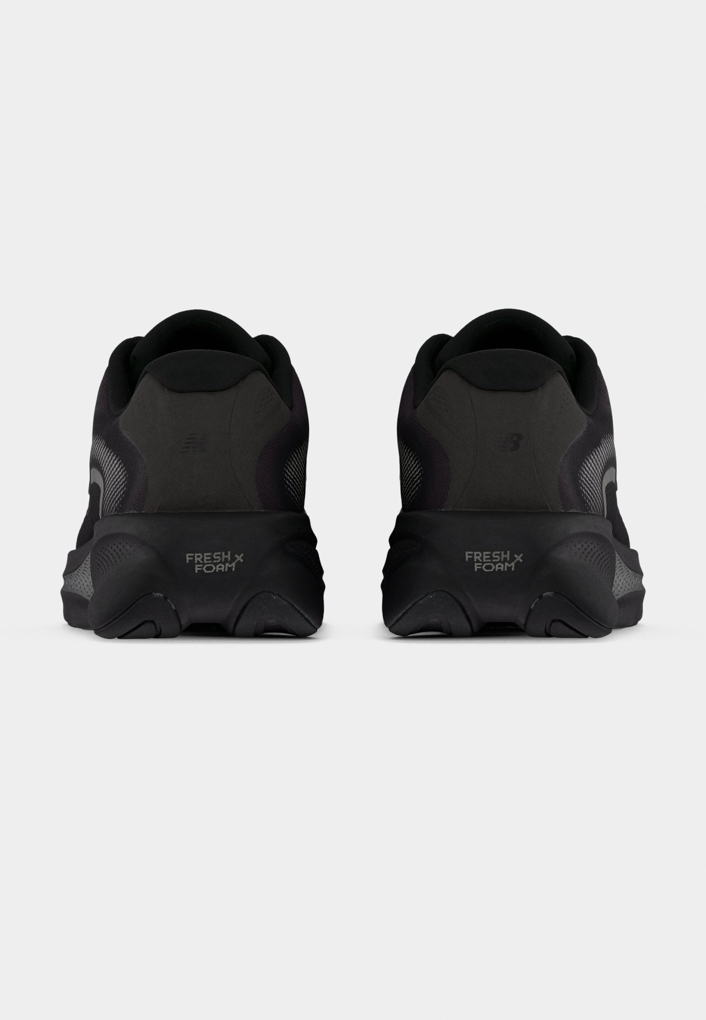 Zapatillas de running negras con parte superior de malla texturizada, suela acolchada y la marca "FRESH FOAM" en el talón. Diseño redondeado y estilo minimalista.