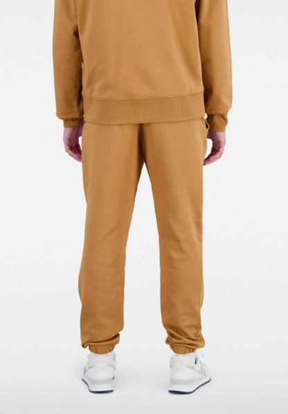 Pantalones de chándal de algodón beige con cintura y puños elásticos. Combinados con zapatillas blancas. La tela parece suave y lisa.