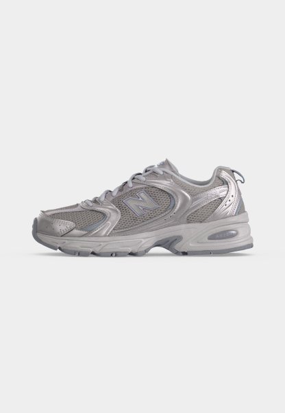 Zapatilla de running New Balance gris con parte superior de malla y sintética, cierre de cordones, suela acolchada y logo en el lateral.