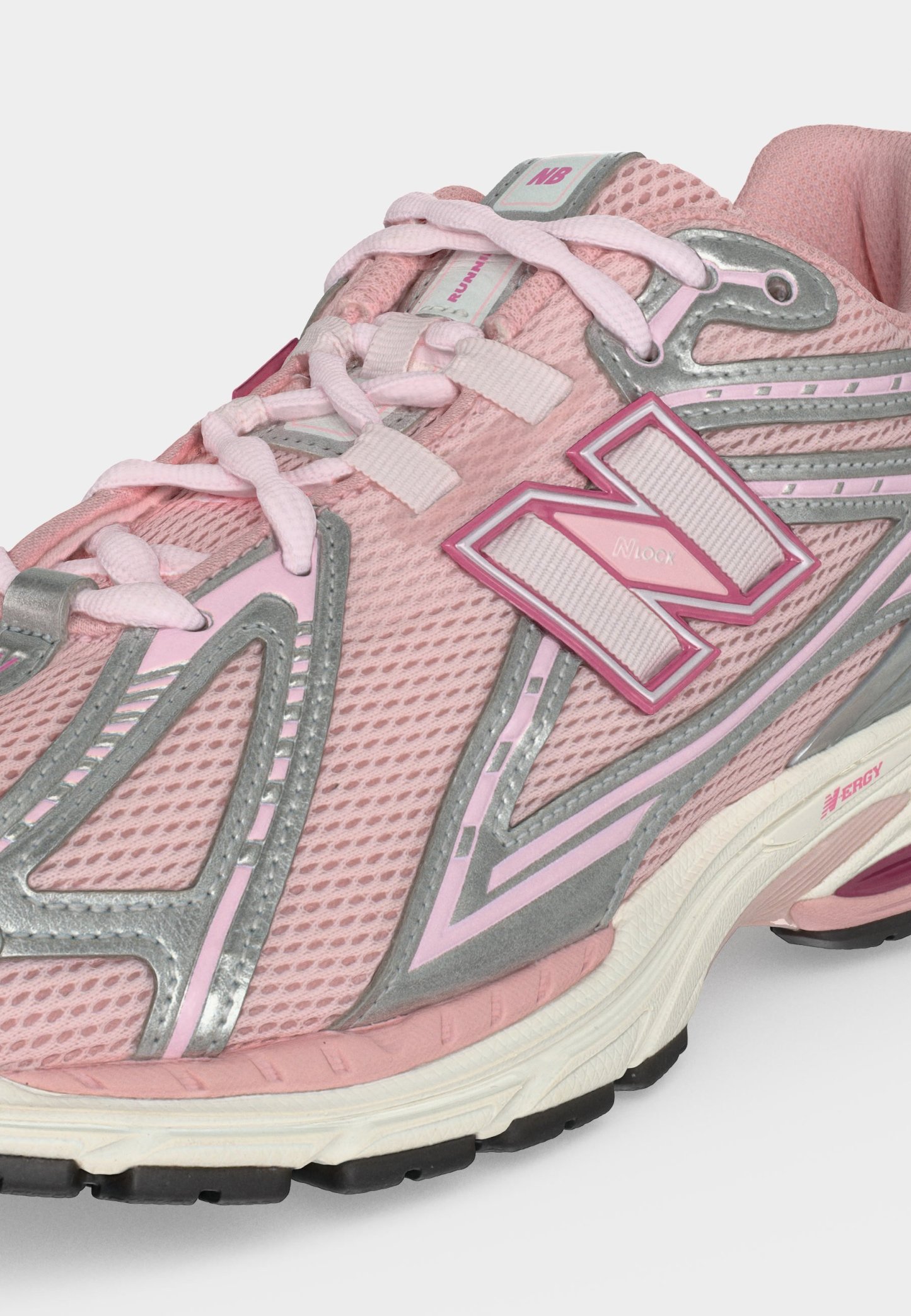 Zapatilla de running New Balance rosa con empeine de malla, detalles reflectantes plateados, logo blanco y rosa, y suela blanca acolchada con dibujo negro.
