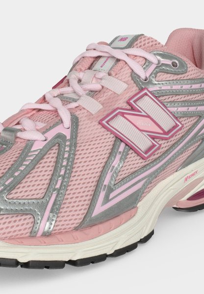 Zapatilla de running New Balance rosa con empeine de malla, detalles reflectantes plateados, logo blanco y rosa, y suela blanca acolchada con dibujo negro.