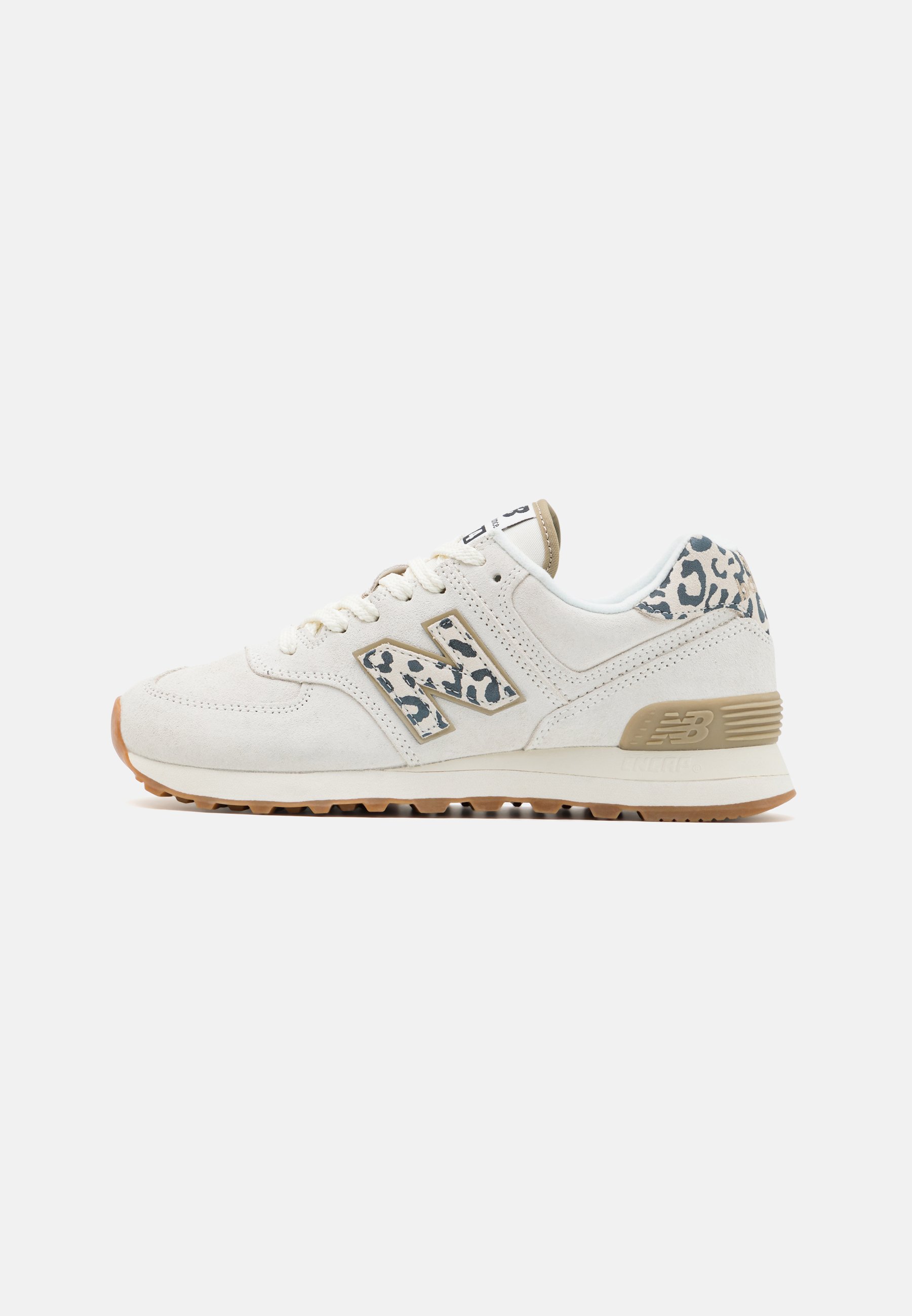 Zapatilla blanca New Balance con suela beige y detalles de estampado de leopardo en el talón y el logo, cierre de cordones, vista de perfil lateral.