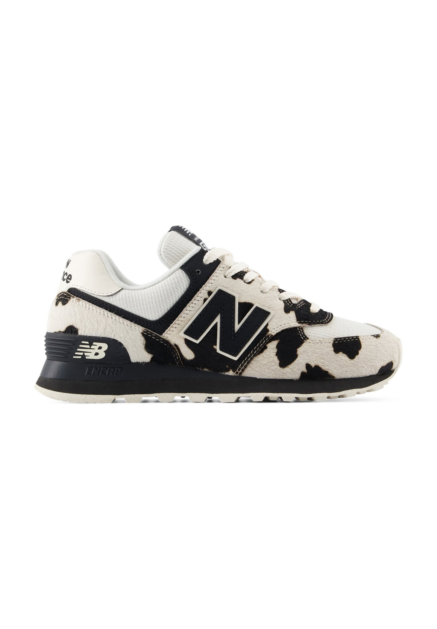 Zapatilla New Balance blanca y negra con estampado de vaca, suela negra y detalles de tela de malla, vista desde el lateral.