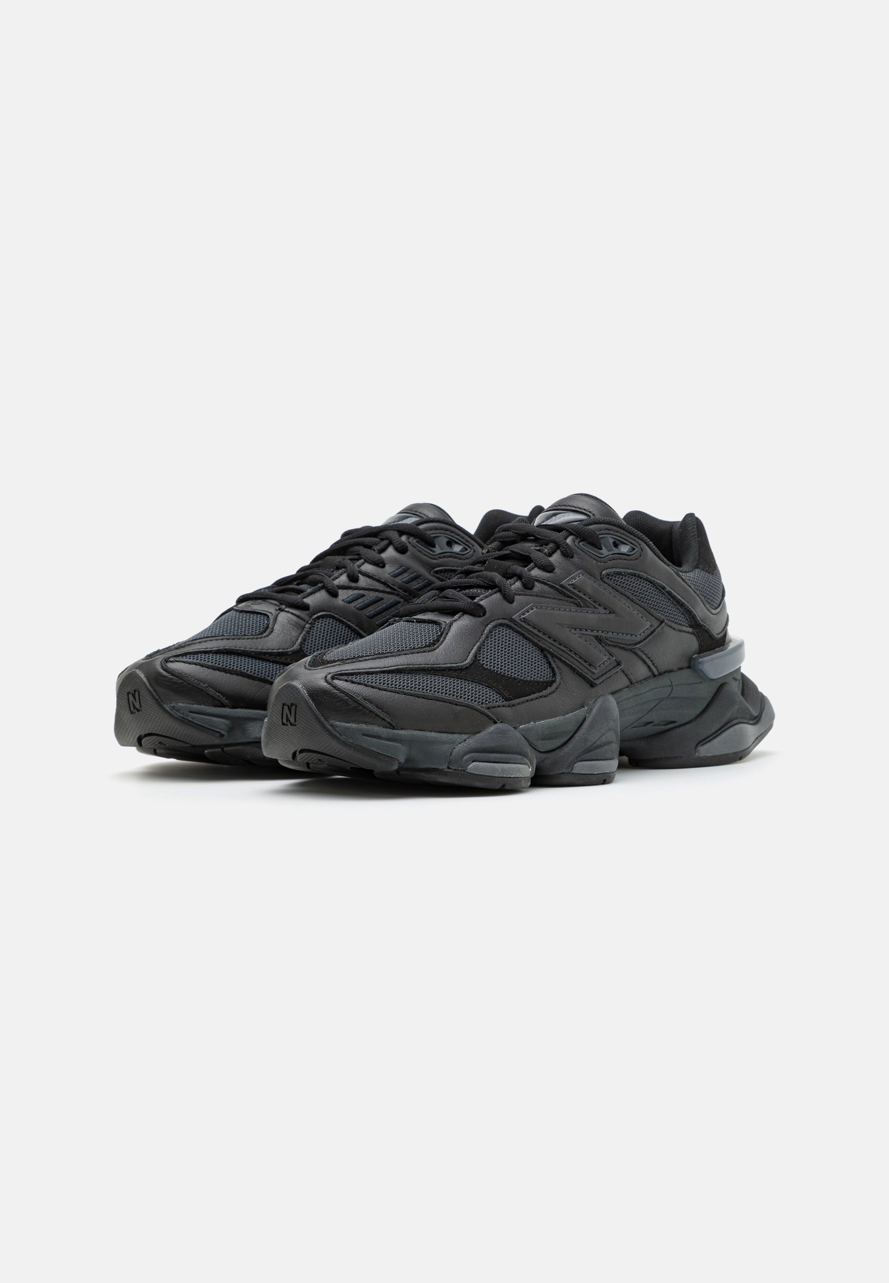 Zapatillas deportivas negras con una mezcla de telas texturizadas y materiales sintéticos, que presentan una suela gruesa y un detalle de amortiguación pronunciado.