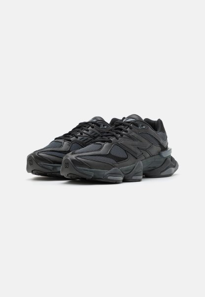 Zapatillas deportivas negras con una mezcla de telas texturizadas y materiales sintéticos, que presentan una suela gruesa y un detalle de amortiguación pronunciado.
