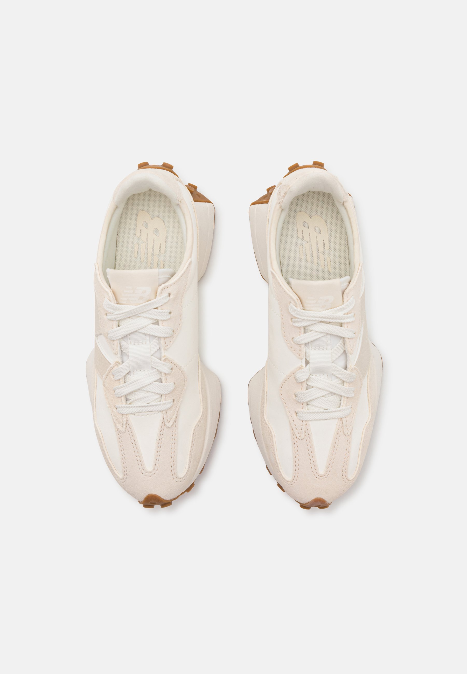 Zapatillas deportivas de color beige claro y blanco con parte superior texturizada, cierre de cordones y suela de goma. Presentan un diseño de panel único y detalles de costura.