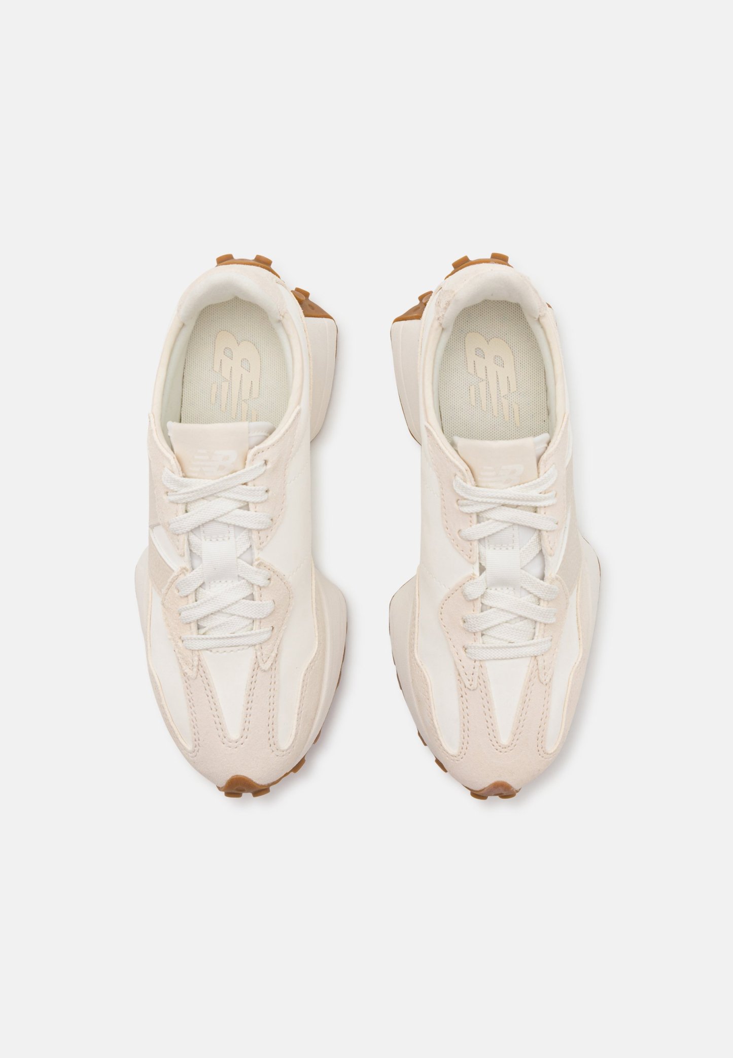 Zapatillas deportivas de color beige claro y blanco con parte superior texturizada, cierre de cordones y suela de goma. Presentan un diseño de panel único y detalles de costura.