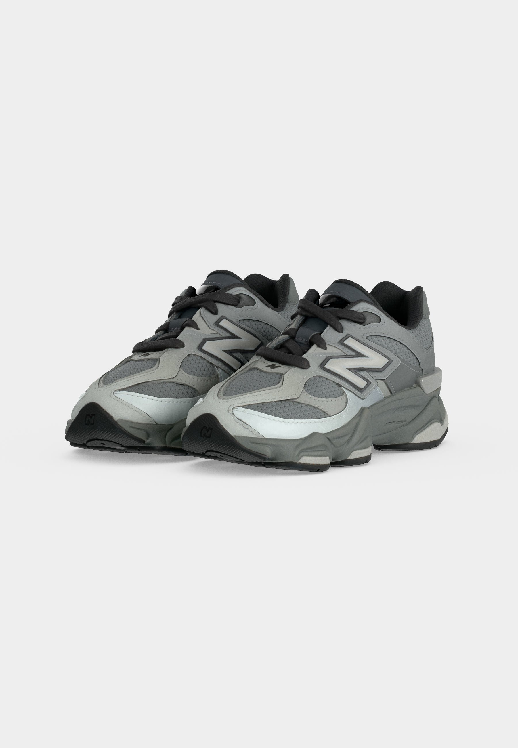 Zapatillas deportivas New Balance en gris y negro con parte superior de malla y sintética, cordones negros y suela gruesa acolchada, mostradas desde un ángulo frontal.