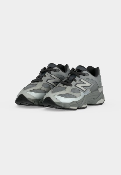 Zapatillas deportivas New Balance en gris y negro con parte superior de malla y sintética, cordones negros y suela gruesa acolchada, mostradas desde un ángulo frontal.