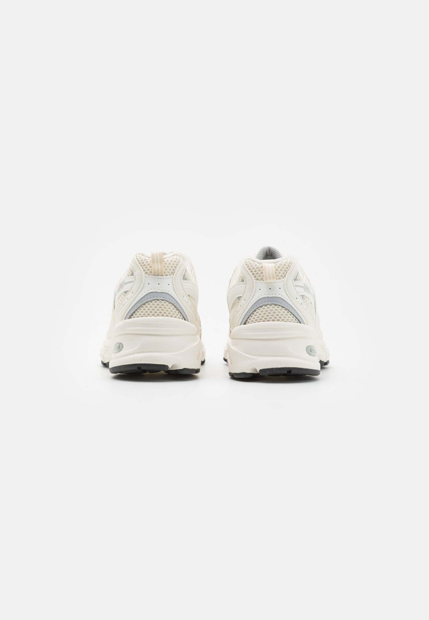 Par de zapatillas para correr confeccionadas con malla sintética de color blanco hueso, vistas desde atrás, sobre un fondo blanco liso.